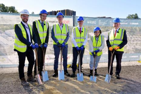 6 people stand at the site of the new weather centre holding spades to mark the ground breaking ceremony