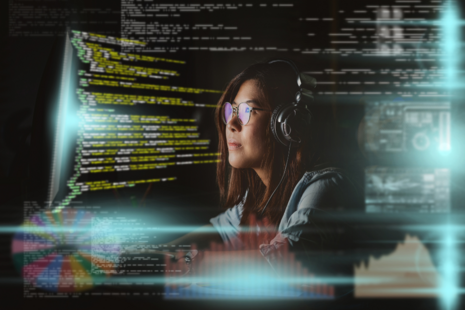 A software developer looking at a screen with overlayed code showing in multiple areas of the image.