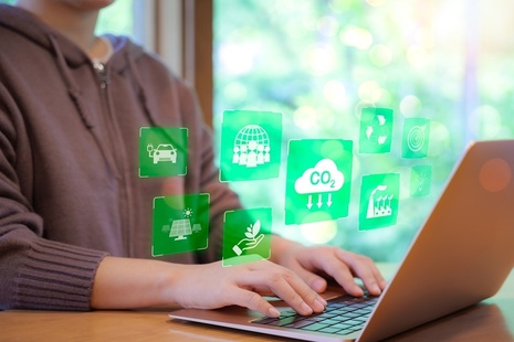 Woman at laptop with various green and environmental symbols floating above. Credit: Shutterstock