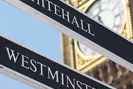 Street view of Big Ben's clock face between 2 signs, one leading to Whitehal and the other leading to Westminster.