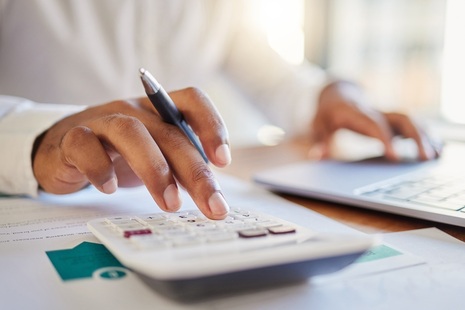 Man with calculator and computer. Credit: iStock Photo