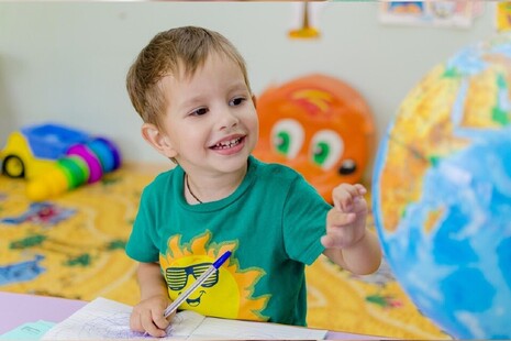 boy in a nursery looking at a globe