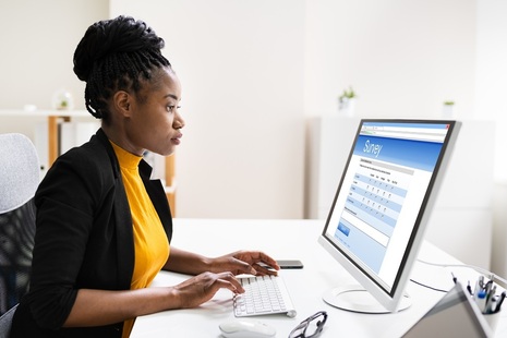 Woman sits at a laptop filling out a survey. Credit: Shutterstock
