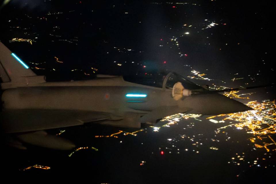 Fighter Jet flying over a city at night