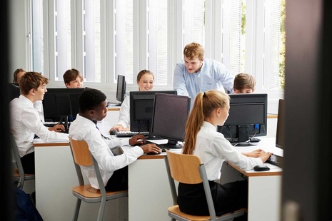 Students using computers, supervised by a teacher