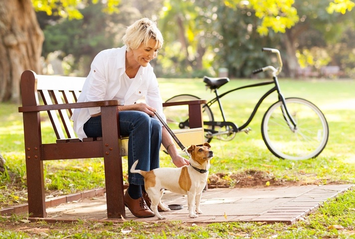 Happy woman in park with dog. Credit: Unsplash