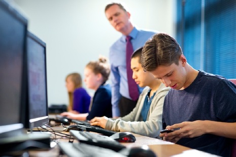 boy using a mobile phone during a school lesson
