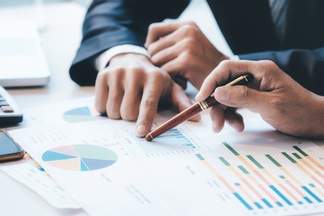 Businessmen with graphs. Credit: Shutterstock.