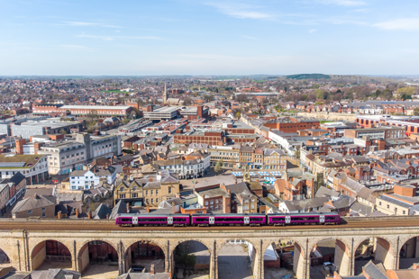 Train going over bridge with city background