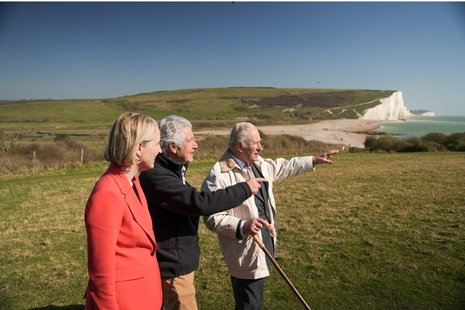Photo showing King Charles, Chair of Natural England Tony Juniper and Environment Secretary Emma Reynolds on a cliff looking out to sea.