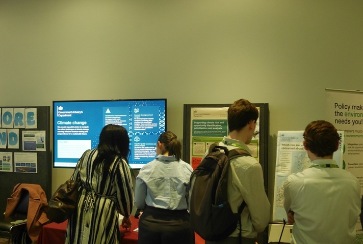 Rear view of 4 people as they look at information displays from GAD at the CSCEN Conference.