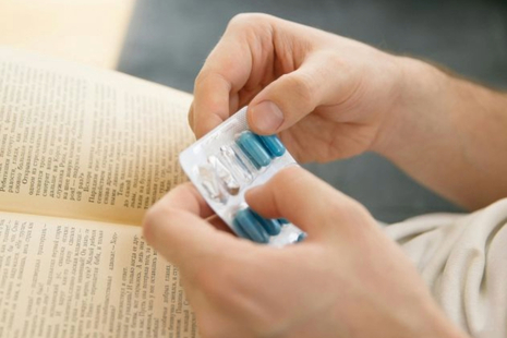 Hands opening a packet of erectile dyfunction tablets.