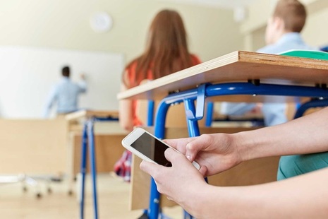 A student using their phone under a desk