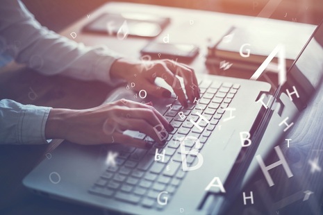 Woman at laptop with hovering letters. Credit: Shutterstock