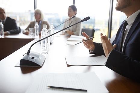 People sit at a table with mics. Credit: iStock Photo