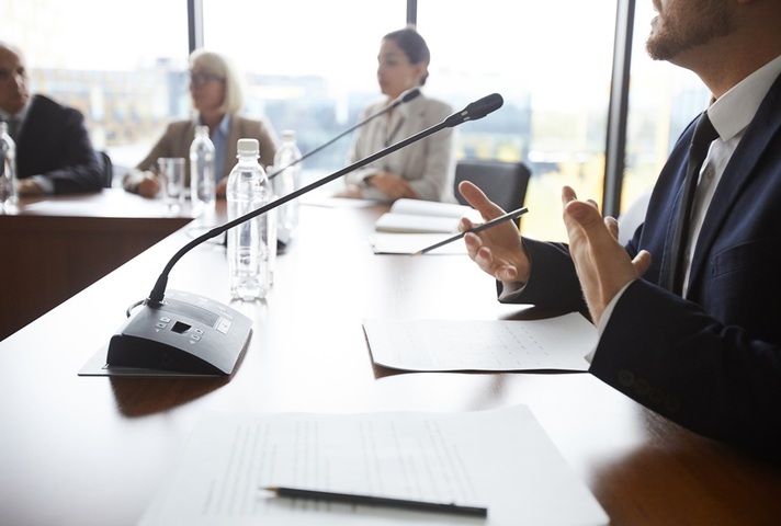 People sit at a table with mics. Credit: iStock Photo