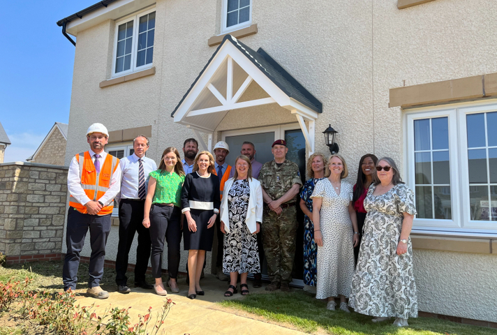 A large group stands in front of a new build house.