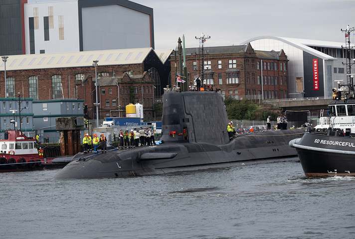 Submarine in the water with people stood on top.