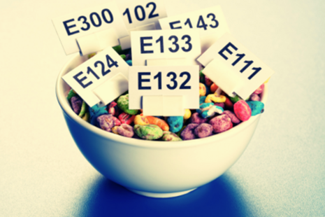 Bowl of brightly coloured cereal with small signs listing various e numbers.