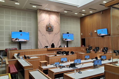 Modern Crown Court courtroom with wood-panelled benches and multiple digital display screens.