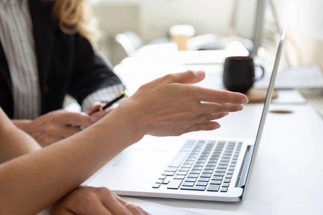 Two people having a discussion and pointing towards a laptop